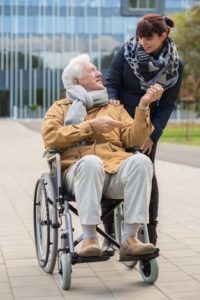 Rollstuhlfahrer mit Pflegerin aus Osteuropa